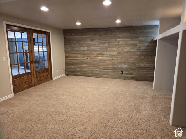 Room featuring an accent wall with horizontal wood planking, recessed lighting, carpeted flooring, built-in shelving, and French doors with glass panes