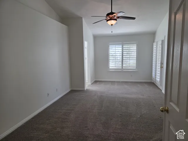 Vaulted ceilings, carpeted flooring, white plantation shutters, and a central ceiling fan with an integrated light fixture