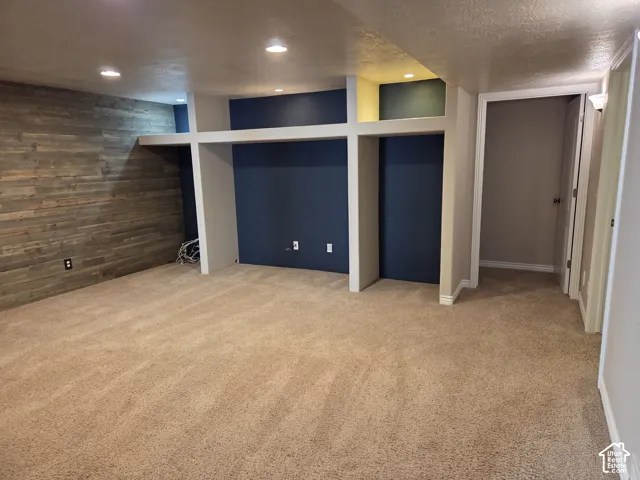 Interior room featuring neutral carpeting, a wood-plank accent wall, recessed lighting, and built-in structural shelving