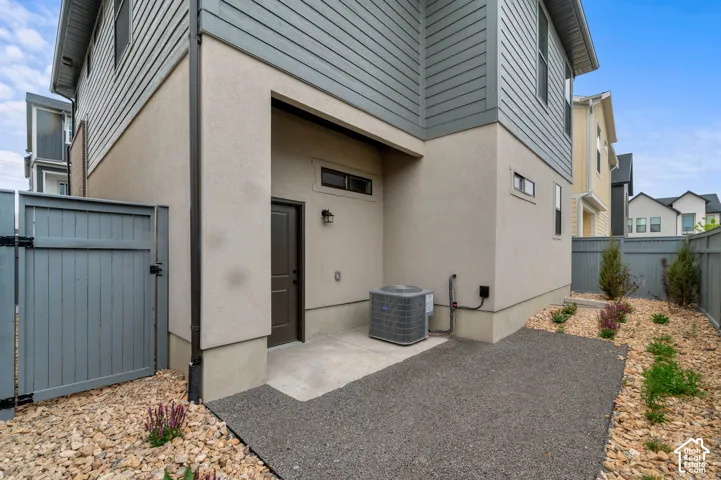 Exterior featuring a mixed-material facade of horizontal lap siding and stucco, a private concrete patio, and fenced-in grounds with rock landscaping