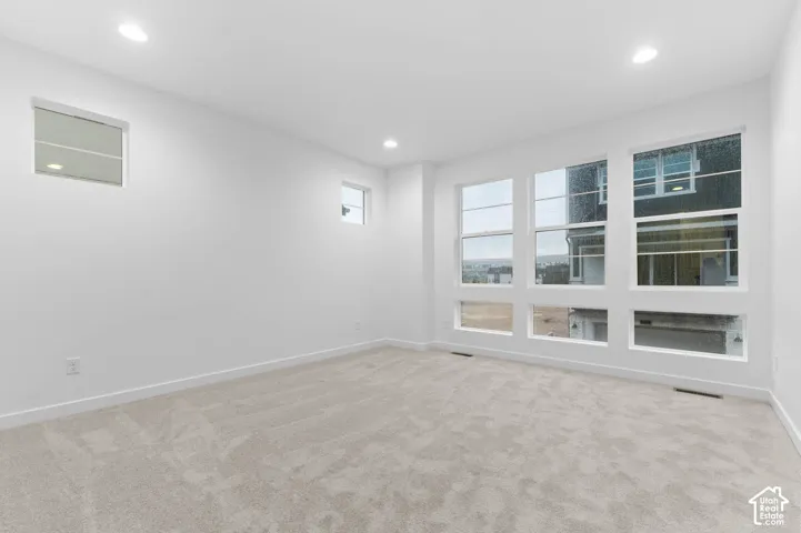 Interior space featuring high ceilings, neutral wall-to-wall carpeting, recessed lighting, and expansive multi-pane windows