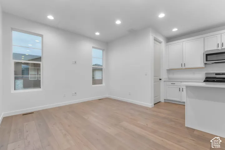 Wood-finish flooring, recessed lighting, white cabinetry, integrated microwave, and quartz-style countertops