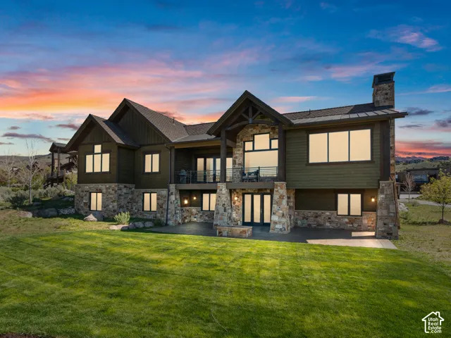 Multi-level exterior featuring stone veneer siding, horizontal lap siding, a metal roof, an upper-level covered deck with cable railing, and a stone-clad exterior fire feature