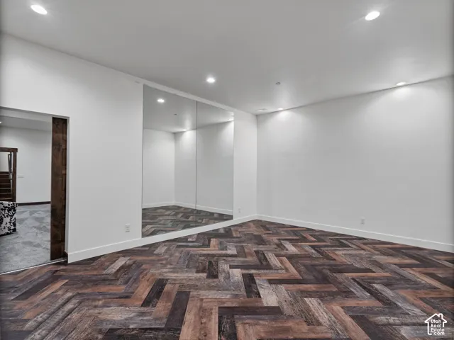 Herringbone wood-finish flooring, floor-to-ceiling wall mirror, recessed lighting, and wooden door frame