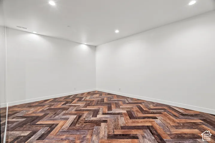 Herringbone-patterned wood-finish flooring complemented by neutral white walls and recessed ceiling lighting