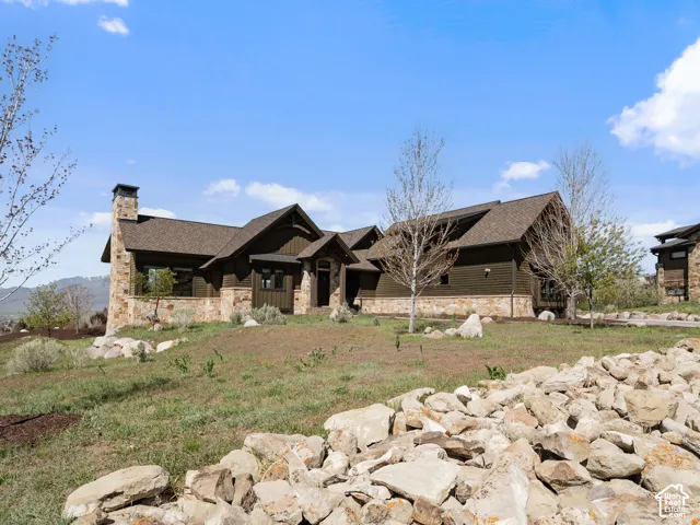 Craftsman-style exterior featuring stone veneer siding, horizontal lap siding, an asphalt shingle roof, and a prominent stone chimney