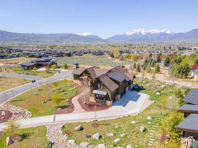 Mountain residence featuring a dark wood-paneled exterior, stone veneer accents, multi-gabled shingle roof, concrete driveway, and winding paver walkway