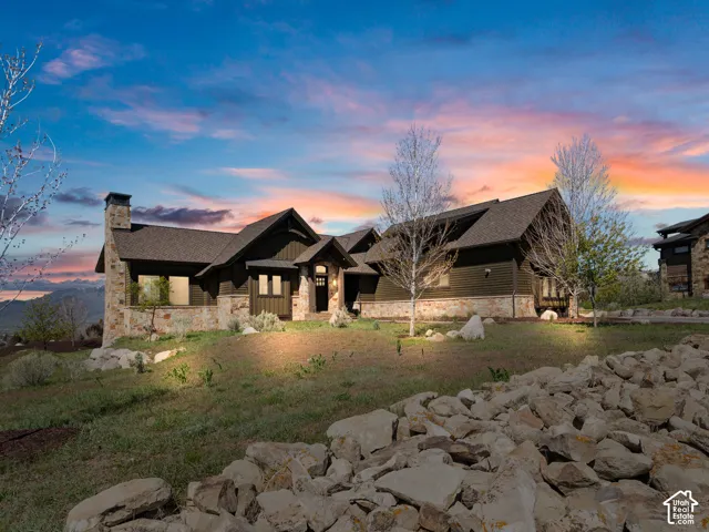 Exterior facade featuring dark horizontal siding, natural stone accents, a prominent stone chimney, and a multi-gabled roofline
