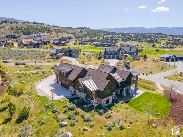 Multi-level residential property featuring dark siding, stone veneer accents, multi-gabled roofline with metal detailing, integrated garage, and a covered patio