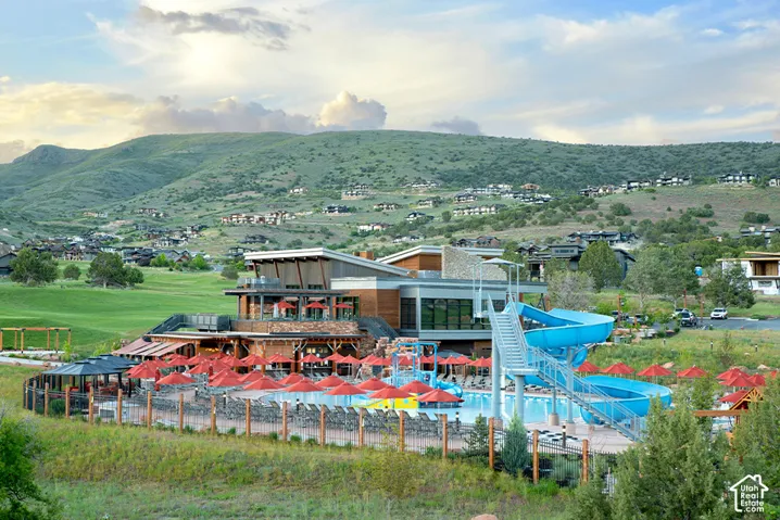 Recreational facility featuring a swimming pool, spiral water slide, multi-level structure with wood-finish siding, stone accents, and expansive mountain terrain
