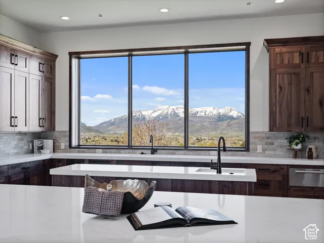 Kitchen featuring dark wood cabinetry, solid surface countertops, a large picture window with mountain backdrop, and matte black plumbing fixtures