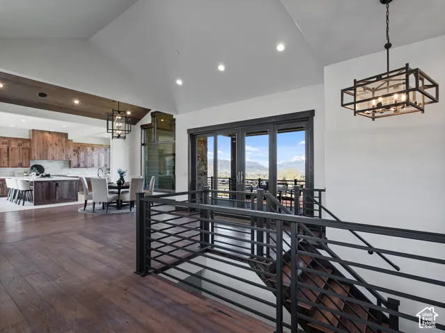 Vaulted ceilings, wood-finish flooring, metal staircase railing, recessed lighting, and multi-panel glass doors