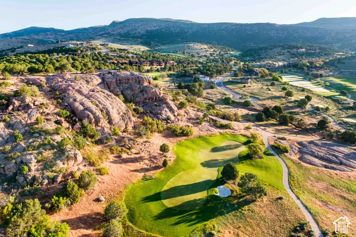 Aerial perspective featuring a natural rock outcropping, expansive mountainous topography, and manicured green space