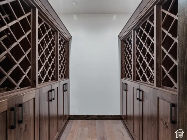 Custom wood cabinetry featuring diamond-pattern wine storage racks, solid-panel lower cabinet doors, and matte black hardware on wood-finish flooring
