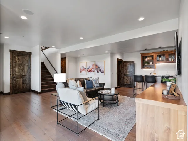 Interior space featuring recessed lighting, wood-finish flooring, custom wood-paneled doors, and a built-in wet bar with cabinetry and stone countertop