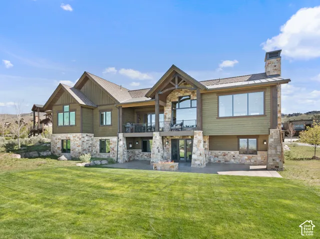 Multi-level exterior featuring stone veneer siding, fiber cement lap siding, a metal roof, an elevated deck with cable railing, and an integrated stone fire pit on the patio