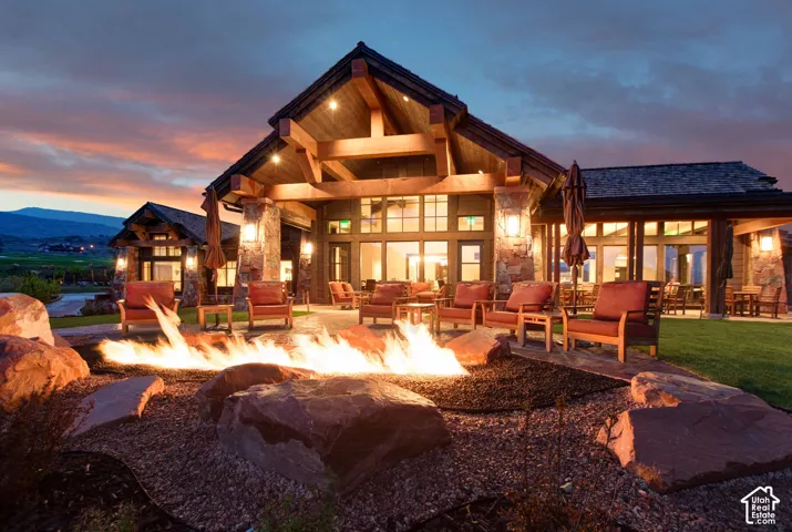 Custom timber-frame architectural details, stone masonry accents, expansive natural stone patio, built-in fire pit, and professional landscape