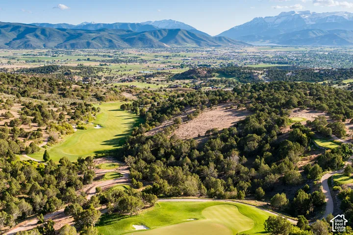 Aerial landscape featuring expansive mountain terrain, rolling hills, native vegetation, and manicured golf course fairways