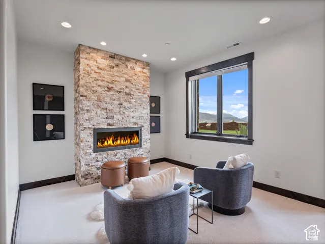 Stacked stone fireplace surround, inset linear hearth, recessed lighting, and expansive window with dark trim