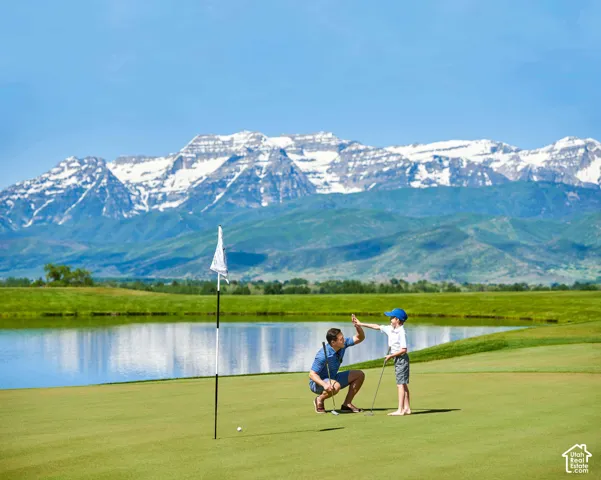 Expansive manicured lawn with a dedicated flagstick, featuring a water feature and prominent mountain backdrop