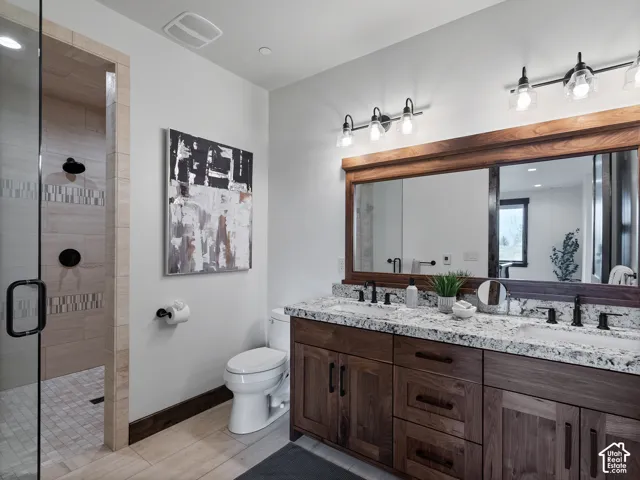 Double vanity with stone-patterned countertops, wood-finish cabinetry, a large wood-framed mirror, dual glass-shade light fixtures, and a walk-in shower with a glass enclosure