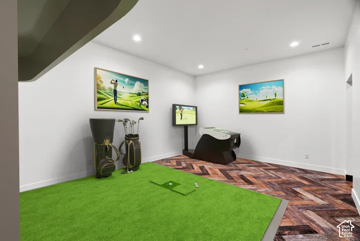 Recreation area featuring wood-finish flooring in a herringbone pattern and recessed ceiling lighting