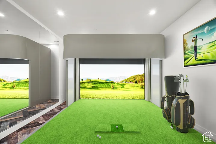 Indoor golf simulator room featuring synthetic turf flooring, floor-to-ceiling mirrored walls, recessed lighting, and a custom curved soffit enclosure
