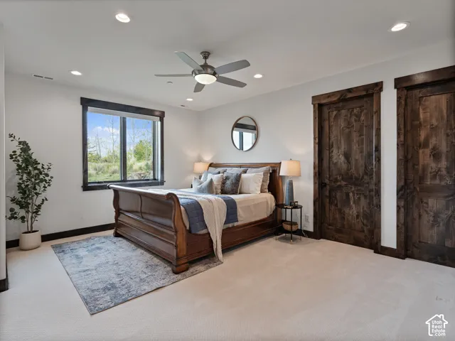 Neutral-toned wall-to-wall carpeting, dark-stained wood interior doors, stained wood window trim, recessed lighting, and a centrally mounted ceiling fan