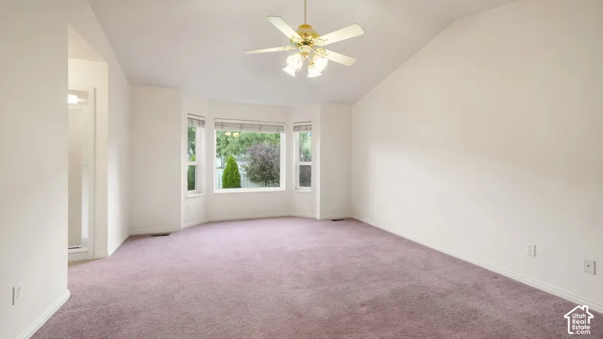 Vaulted ceilings, bay window, and a ceiling fan with integrated lighting