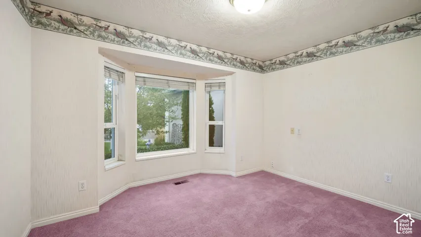 Spacious interior featuring a large bay window, wall-to-wall carpeting, and a flush-mount ceiling light fixture