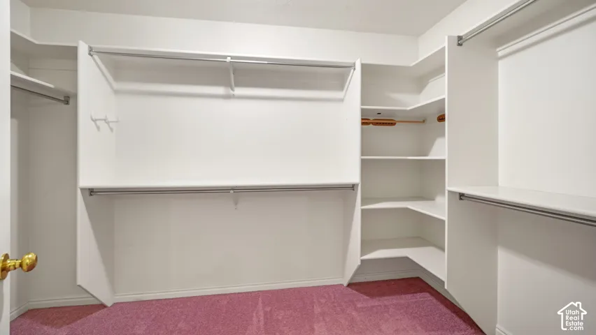 Walk-in closet featuring white built-in shelving, integrated corner storage units, and dual-level hanging rods