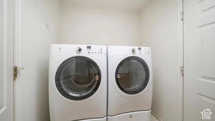 Laundry area featuring white front-load washer and dryer units with integrated storage pedestals and paneled doors