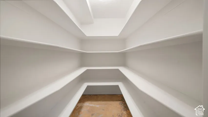 Walk-in storage featuring multi-level built-in shelving, white painted finishes, and polished concrete flooring