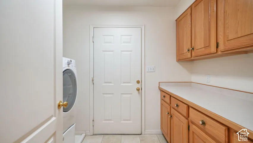 Dedicated room featuring wood-finish cabinetry, solid-surface countertop, tile flooring, and a six-panel exterior door