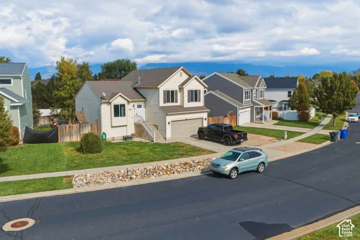 Two-story residence featuring vinyl siding, an attached two-car garage, mountain backdrop, and front yard landscaping with rock ground cover