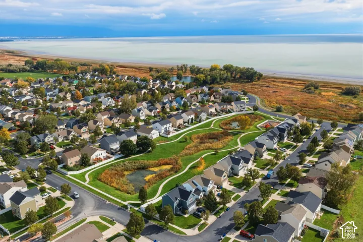 Aerial perspective of a residential community featuring extensive green space, winding paved walking paths, multiple natural ponds, and proximity to the shoreline