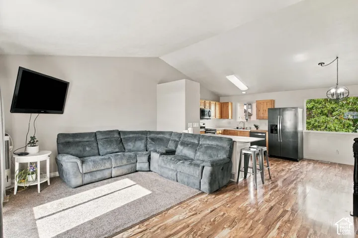 Vaulted ceilings, wood-finish flooring, kitchen cabinetry, and an attached island
