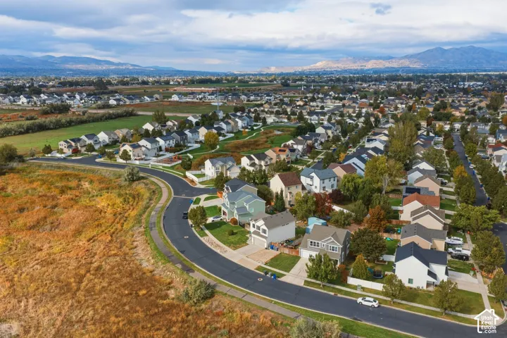 Aerial perspective of a suburban neighborhood featuring paved streets, established landscaping, mature trees, and mountainous topography in the distance