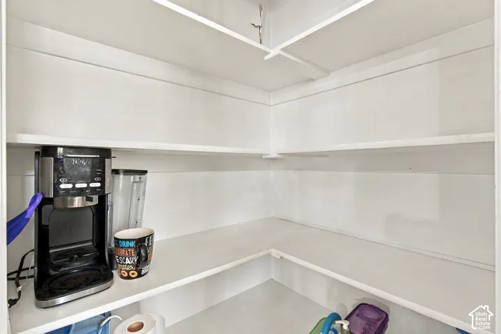 Storage area featuring floor-to-ceiling white painted shelving with an L-shaped configuration