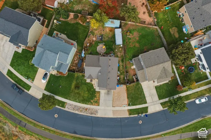 Aerial perspective of a residential property situated on a cul-de-sac, featuring a private driveway, concrete sidewalk, fenced backyard, and mature landscaping