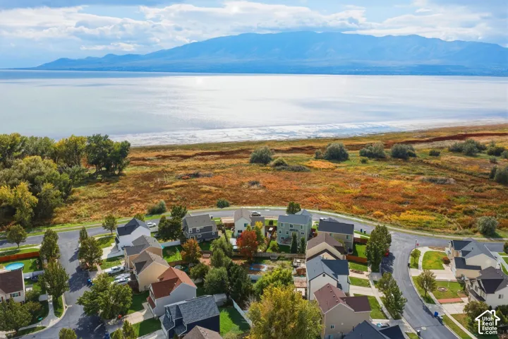 Aerial perspective featuring residential lots with proximity to open natural terrain, shoreline, and mountain backdrop