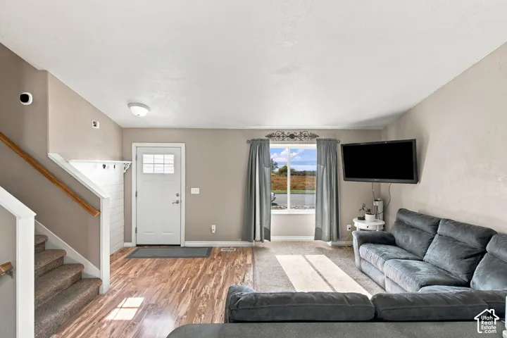 Interior space featuring wood-finish flooring, a white-paneled entry wall with integrated shelf, staircase with wood handrail, and a picture window