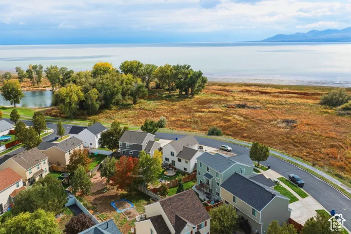 Aerial perspective showcasing proximity to open water, expansive natural terrain, mature trees, and a paved road network