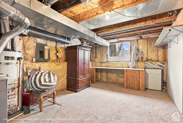 Unfinished utility space featuring exposed joist ceilings, metallic HVAC ductwork, integrated electrical panel, thermal insulation, and a built-in wooden workbench