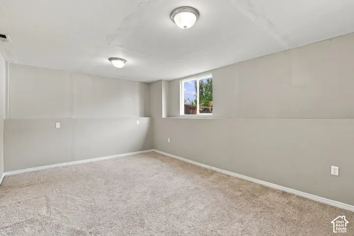 Neutral-toned room featuring neutral carpeting, light-colored wall paint, two flush-mount dome light fixtures, and a single-pane window