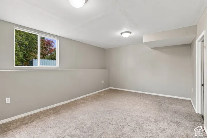 Neutral-toned interior space featuring wall-to-wall carpeting, dual ceiling-mounted light fixtures, and a horizontal sliding window