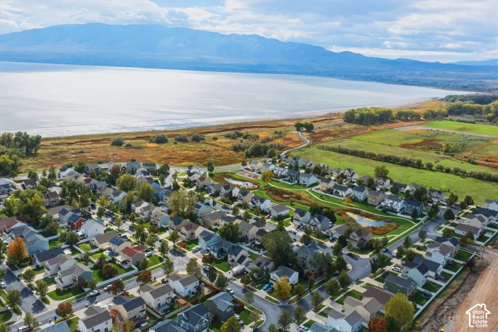Aerial perspective featuring proximity to a large body of water, prominent mountain backdrop, interconnected neighborhood pathways, and open green space