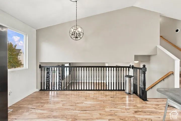 Vaulted ceilings, wood-finish flooring, spherical metal pendant lighting, and a black baluster railing