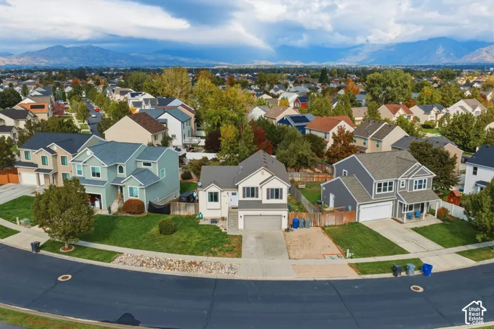 Two-story residence featuring a shingled roof, neutral-toned siding, a concrete driveway, an attached garage, and mountain scenery