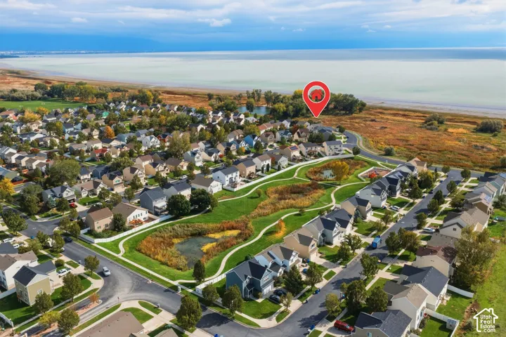 Aerial perspective featuring coastal proximity, multi-story residential architecture, and expansive community green space with meandering pathways and natural water features